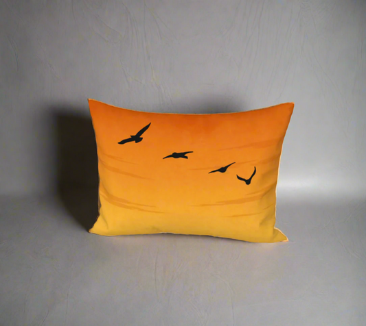 Orange pillow with black bird illustrations on a white background